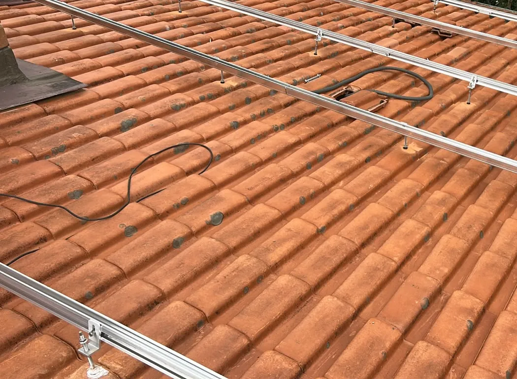 Trilhos e pontos de fixação sobre telhas na instalação de Bertioga.