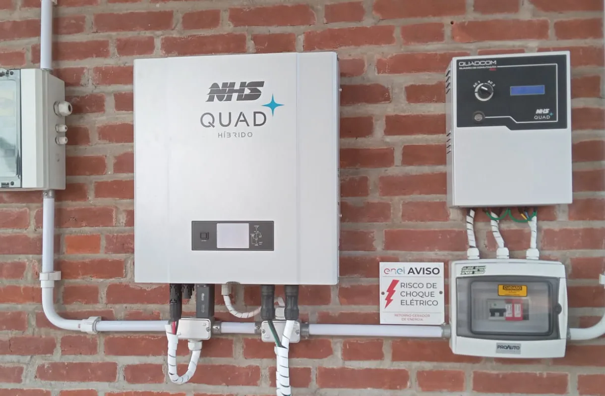 Inversor híbrido e quadros elétricos instalados em parede.